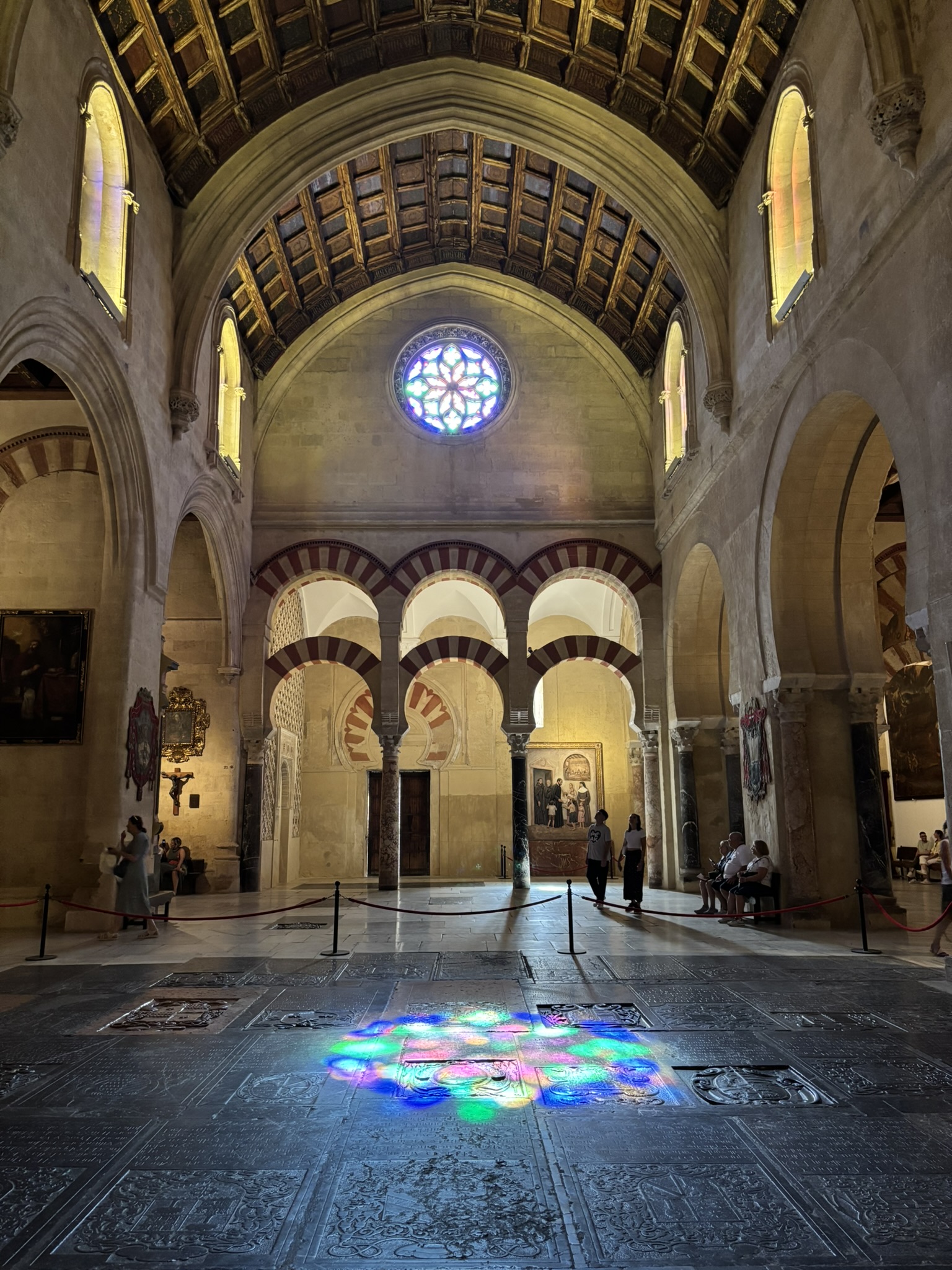 Interior arches of the Mezquita Córdoba Mosque-Cathedral with a stained glass window reflecting on the floor of the building